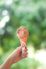 Ice cream cone. A lady's hand holding a chocolate ice cream cone in the summer day. B