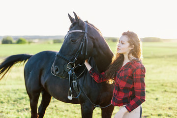 Obraz premium Young girl standing next to a beautiful dark horse.