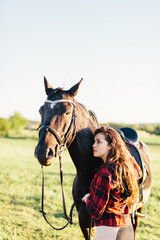 Obraz premium Young girl hugging purebred black horse on the field.