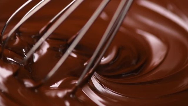 Chocolate. Mixing melted dark chocolate with a whisk. Closeup of liquid hot chocolate swirl. Confectionery. Slow motion 4K UHD video 3840X2160