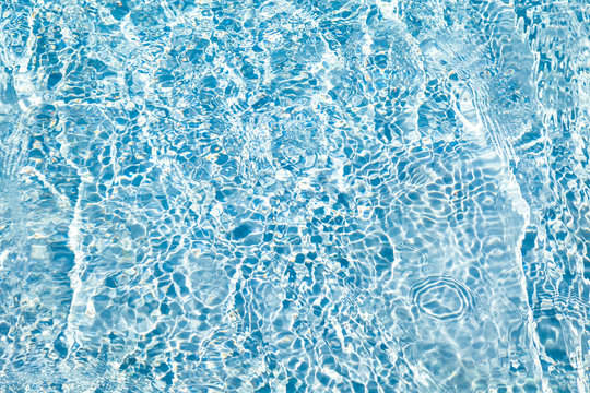 Texture of sparkling blue water. The surface is crystal clear water, beautifully iridescent in sunny day. 