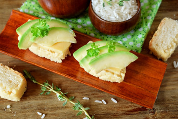 Sandwiches with cheese and avocado slices on pieces of rice gluten free bread