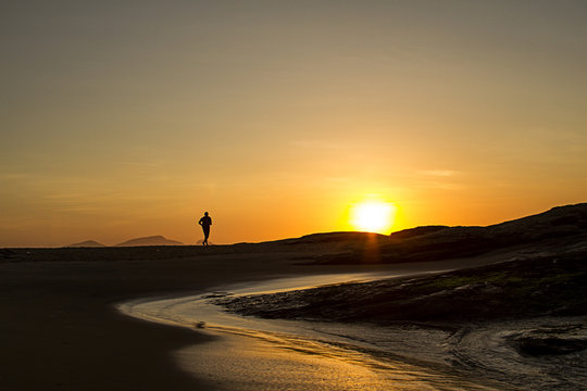 Athlete running on the beach of Macaé Rio de Janeiro Brazil at sunrise