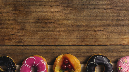 Round donuts, cookies, and fruitcake, flat lay dessert on wooden table decorate with candy