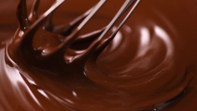 Chocolate. Mixing melted dark chocolate with a whisk. Closeup of liquid hot chocolate swirl. Confectionery. Slow motion 4K UHD video 3840X2160