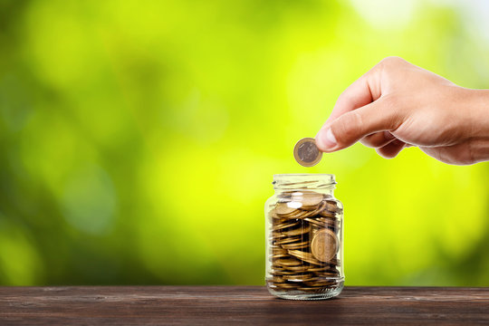 hand put money coins to glass jar