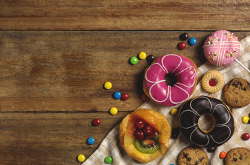 Round donuts, cookies, and fruitcake, flat lay dessert on wooden table decorate with candy
