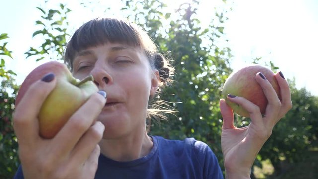 Healthy eating - Young woman funny face bite and chew ripe juicy apples in the garden