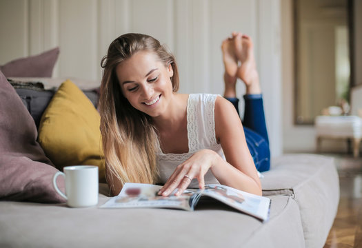 Happy young woman reading a magazine