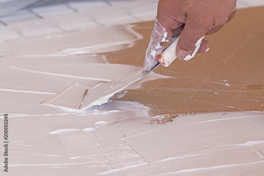 Wall mural Hand spreading plaster with a spatula on a surface.