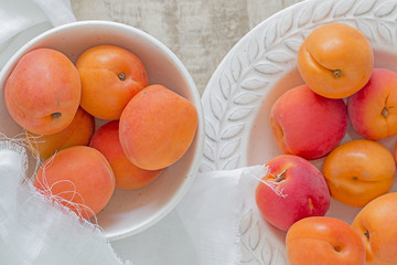 Many ripe apricots in a plate and a bowl.