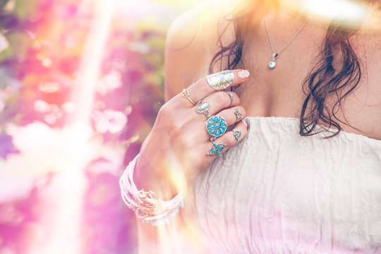 closeup of young woman hand with  lot of boho style jewrly, rings and bracelets outdoor light leak