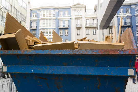metal container with debris and wood waste in city street