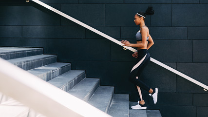 Full length of young female exercising in a city, running upstairs
