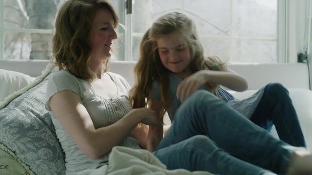 Slow motion of mother reading book in bed then hugging and comforting daughter / Pleasant Grove, Utah, United States