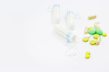 Tampons and pills on a white background