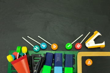 Closeup of colorful school supplies with copy space on blackboard background. Back to school.