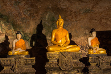 golden buddha statues along the wall inside the cave