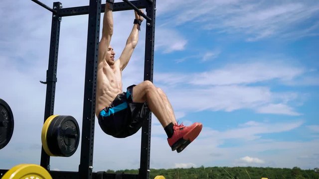 Athletic male sportsman training outside on special equipment.