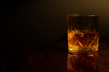 Whiskey in a glass tumbler isolated on a dark wooden table