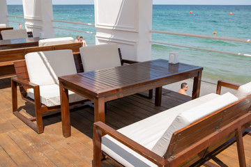 Interior of summer club with pool at sea. Hotel pool. Resort Pool Club at ocean. Tourist resort. Pool with clean water, sun beds, folded tents, greens trees, flowers. Chaise lounges in swimming pool.