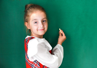 Child girl  with chalk on green background.