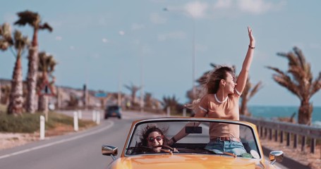 Women having fun and enjoying the sun in convertible car - Powered by Adobe