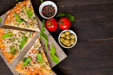 Pieces of pizza with ham, mushrooms and tomatoes on a dark, wooden background. Fast food.