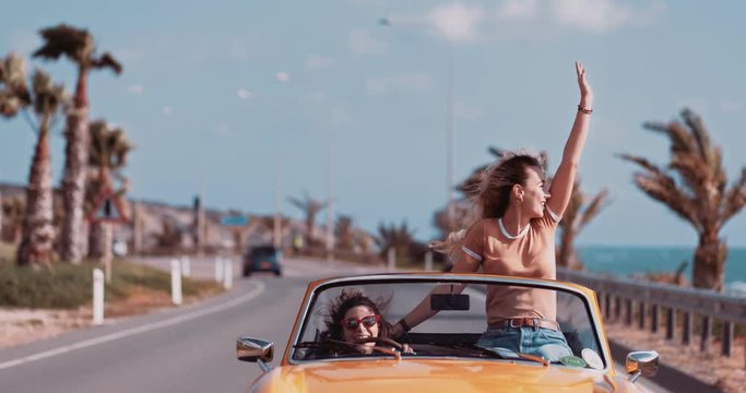 Women having fun and enjoying the sun in convertible car