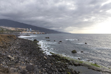 Fototapeta na wymiar Puerto de la Cruz, Tenerife, Canary Islands - view of colorful houses, sea and volcanic-sand beach. Black beach in tenerife