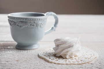 White homemade zephyr with cup of tea on the wooden boards