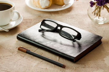 Black leather notepad black-rimmed spectacles pen