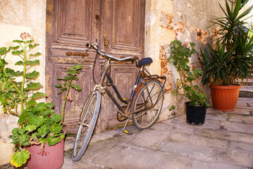 Fototapeta na wymiar Vintage Bicycle Leaning against old door in Chania city, Greece
