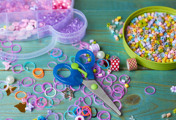 Accessories for creativity. Beads, mosaic, scissors and colored rubber bands on a blue background.