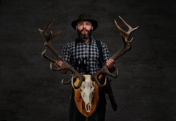 Bearded hunter in a fleece shirt and hat holds his trophy.