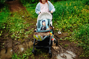 Little baby boy sitting in the stroller at the green garden.