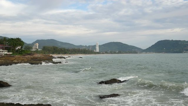 sea wave hit the rock shore seascape , Patong sand beach Phuket  parasail , high building, tree and mountain are  background ,