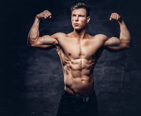 Fototapeta na wymiar Beautiful shirtless young man model with nice muscular body posing at a studio.