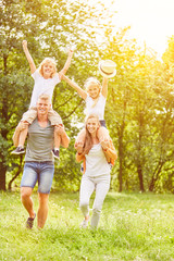 Fototapeta premium Eltern tragen Kinder huckepack im Sommer