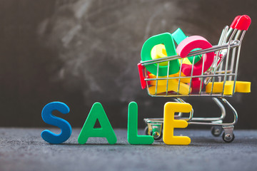 sale, discount, black Friday concept with bright inscription Sale on a dark background, consumer trolley with letters Close up
