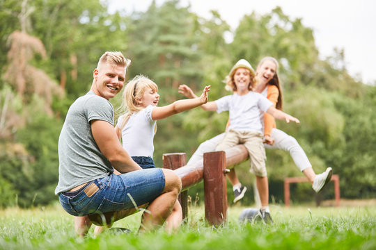 Vater schaukelt mit Kindern auf dem Spielplatz