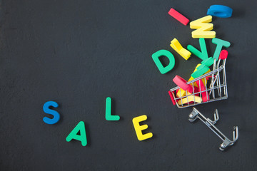 sale, discount, black Friday concept with bright inscription Sale on a dark background, consumer trolley with letters Copyspace Top view.