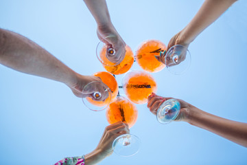 a few cocktails in hands of people on blue background. a circle of cocktails apprelated spritz in...