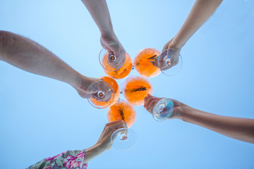 a few cocktails in hands of people on blue background. a circle of cocktails apprelated spritz in...