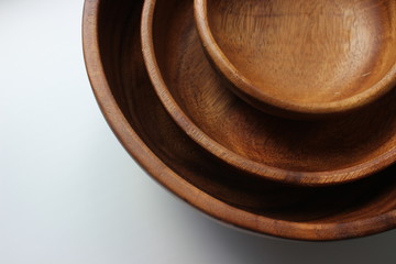 Three wooden empty bowls for eating, cooking salad stacked on top of each other on white background