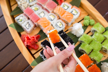 chopsticks in a female hand with a roll. set of rolls on the ship . set sush. Japanese food
