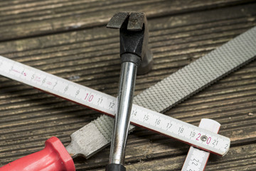 Hammer, Zollstock und Feile gekreuzt auf einem Holztisch
