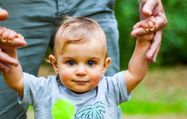 Portrait of a Baby Boy with Blue Eyes in park. trust family hands of child son and father on field nature outdoor