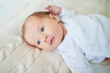 Baby girl lying on bed in nursery