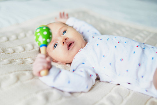 Newborn baby girl with colorful wooden toy